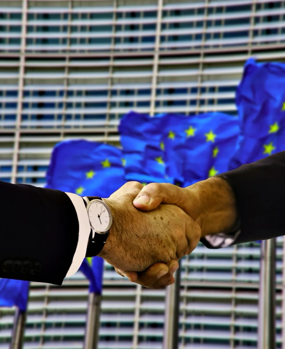 Photo of shaking hands in front of EU flag